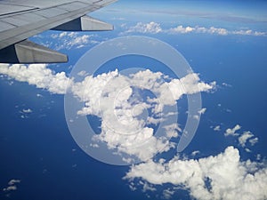 The airplane wing above the blue cloudy sky