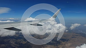 Airplane wing above the clouds and mountains