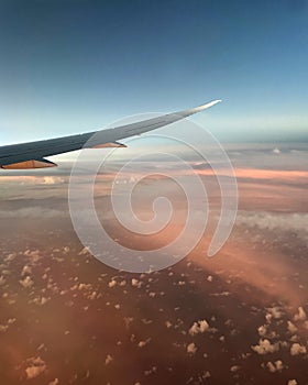 Airplane wing above the clouds, pink and blue