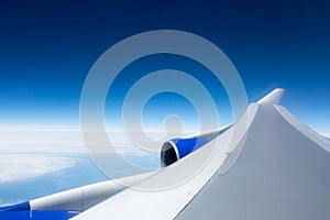 Airplane wing against blue sky from the porthole