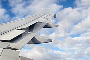 Airplane wing against clouds in a blue sky