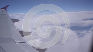 Airplane wing on a background of blue sky and white clouds