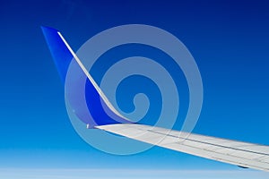 Airplane wing on the blue sky with clouds