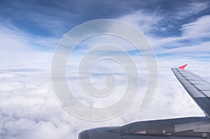 Airplane wing in the blue sky with clouds