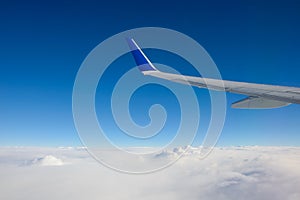 Airplane wing with blue sky has a lot of windows