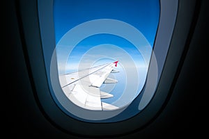 Airplane wing on blue sky, view through plane window, with copy space