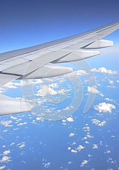 Airplane wing on blue sky with white clouds.