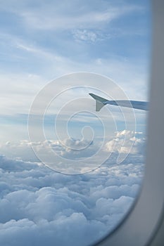 Airplane wing and cloudscape through porthole