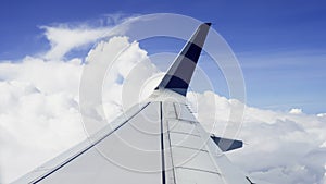 Airplane Wing in cloudy sky. Passenger aircraft flying above the beautiful scenery of white fluffy clouds in the blue