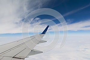 Airplane wing and dark blue sky with white clouds in flight