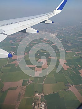 Airplane wing and fields aerial view from aeroplane window