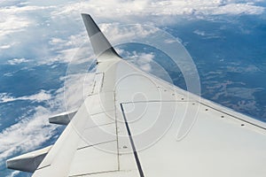 Airplane wing in flight above the clouds, horizon of the earth.