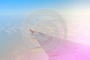 Airplane Wing in Flight from window above clouds and sky.