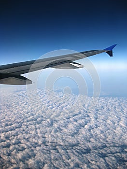 Airplane wing over blue sky with clouds view