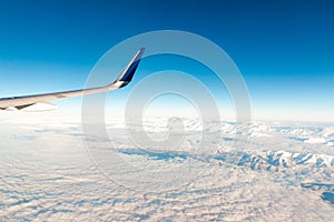 Airplane wing over cloudy mountains