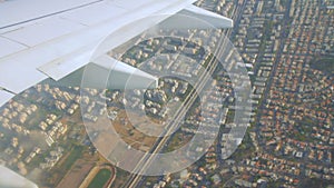 Airplane wing on the sky and over land with building of Tel Aviv