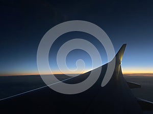 Airplane wing in the sky at sunset.