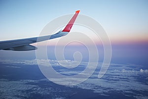 Airplane wing at sunrise sky. Travel