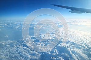 Airplane wing on vibrant blue sky and fluffy white clouds view from the plane window during flight