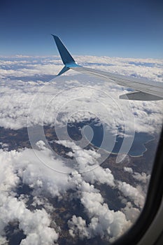 An airplane wing with a view of the bright blue sky and clouds