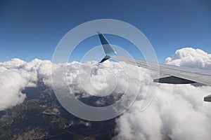 An airplane wing with a view of the bright blue sky and clouds