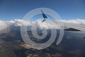 An airplane wing with a view of the bright blue sky and clouds