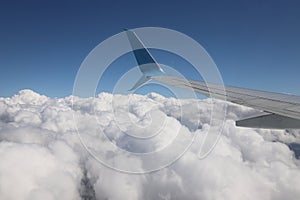 An airplane wing with a view of the bright blue sky and snow-white clouds