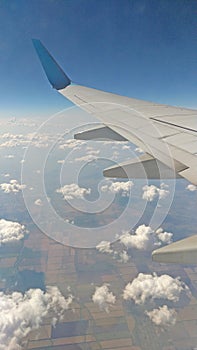 Airplane wing view out of the window on the cloudy sky background. Holiday vacation background. Wing of airplane flying above