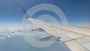 Airplane wing view out of the window on the cloudy sky background. Holiday vacation background. Wing of airplane flying above
