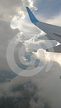 Airplane wing view out of the window on the cloudy sky background. Holiday vacation background. Wing of airplane flying above the