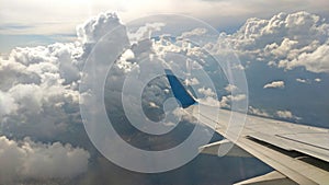 Airplane wing view out of the window on the cloudy sky background. Holiday vacation background. Wing of airplane flying above the