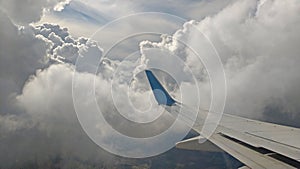 Airplane wing view out of the window on the cloudy sky background. Holiday vacation background. Wing of airplane flying above the