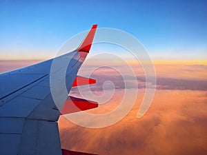 Airplane wing view over clouds at sunset