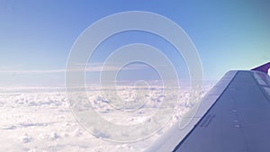 Airplane wing on white clouds and blue sky landscape. View from window flying aircraft in blue sky with white clouds