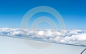 Airplane wing, white porous clouds and beautiful blue sky. Copy space. Selective focus