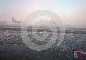 Airplanes are getting ready to fly on foggy morning. The picture of foggy morning at the airport taked by mobile phone photo