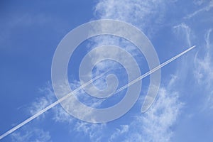 Airplanes leaves trace on among cloud on blue sky. View from below on the trails from plane. Travel concept background