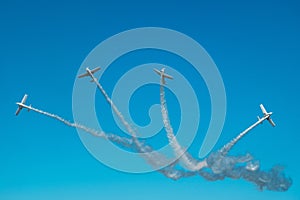 Airplanes with white smoke traces on air show. Pilots make tricks on jets at blue sky background