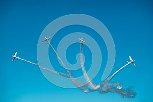 Airplanes with white smoke traces on air show. Pilots make tricks on jets at blue sky background