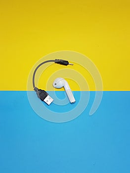 airpod with black lead placed on a yellow and froze backgroumd background