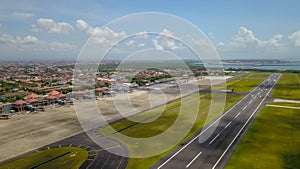 Airport - aerial view with runways, taxis, grass and air-crafts. Aerial view to Ngurah Rai airport. The plane goes down