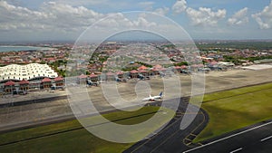 Airport - aerial view with runways, taxis, grass and air-crafts. Aerial view to Ngurah Rai airport. The plane goes down