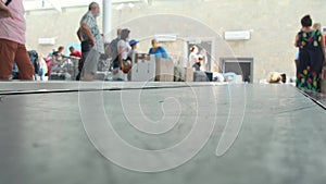 Airport baggage belt. Baggage claim. Bottom view. People in the background are waiting for their luggage. 4k, real time