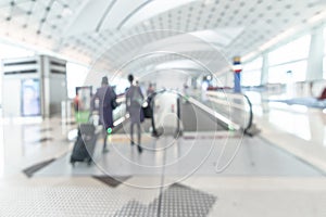 Airport blurred background interior with people travelers and air hostess with luggage on passage escalator walkway in