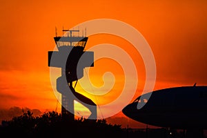 Airport control tower at sunrise, with jet silhouette