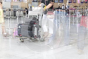 Airport luggage Trolley with suitcases, unidentified man woman walking in the airport, station, France. Blur motion, double exposu