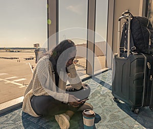 Airport phone travel woman using mobile smartphone while waiting for plane flight texting sms message. Technology and travel