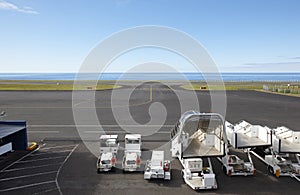 Airport runway close to the ocean with auxiliary vehicles