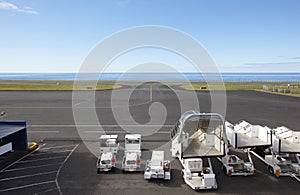 Airport runway close to the ocean with auxiliary vehicles photo