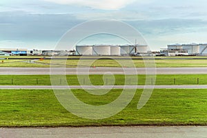 Airport runway in front of Fuel Storage Tanks and industrial storage site.